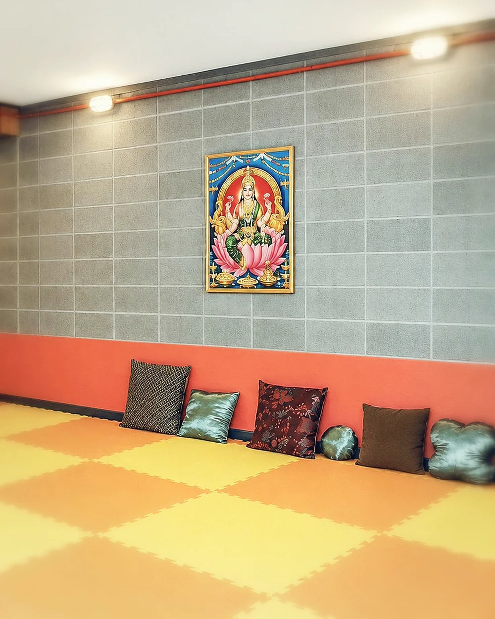 Espaço para prática com tatame, almofadas e quadros de Ganesha e Lakshmi